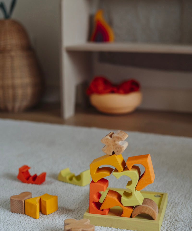 The yellow an natural wooden blocks from the Grimm's yellow building set stacked up on top of each other on the yellow tray. These Grimm's toys are part of a wide range of wooden toys available here at Babipur. 