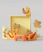 The yellow and natural wooden blocks from the Grimm's yellow building set used in a small world play scene with the Grimm's friends wooden peg dolls. These Grimm's toys are part of a wide range of wooden toys available here at Babipur. 