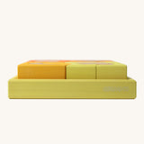 A side profile view of the yellow tray . Grimm's Building Set in Yellow. Wooden blocks in variopus shades of yellow and natural wood in a yellow coloured wooden storage tray. These Grimm's toys are part of a wide range of wooden toys available here at Babipur. 