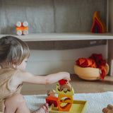 A child playing with the yellow and natural wooden blocks from the Grimm's yellow building set. The child is stacking them on top of each other on the yellow coloured storage tray that they come with. These Grimm's toys are part of a wide range of wooden toys available here at Babipur. 