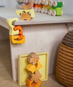 A child playing with the Grimm's Building Set in Yellow placing them on a table. Wooden blocks in various shades of yellow and natural wood in a yellow coloured wooden storage tray. These Grimm's toys are part of a wide range of wooden toys available here at Babipur. 