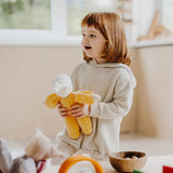 Child holding a Grimms yellow soft Waldorf doll showing size