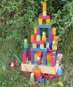 Grimm's small stepped counting blocks stacked up outdoors with Grimm's friends peg dolls placed on the stack