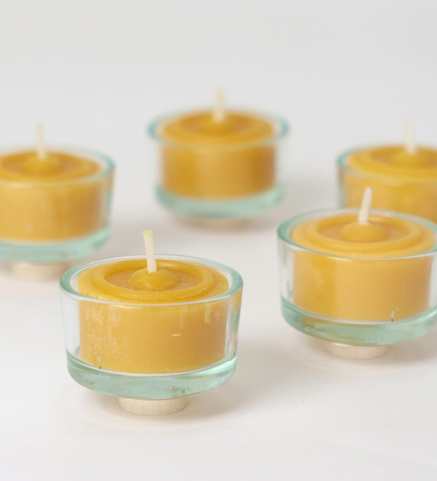 A closeup of the Grimm's beeswax tealights in the glass tealight holders.