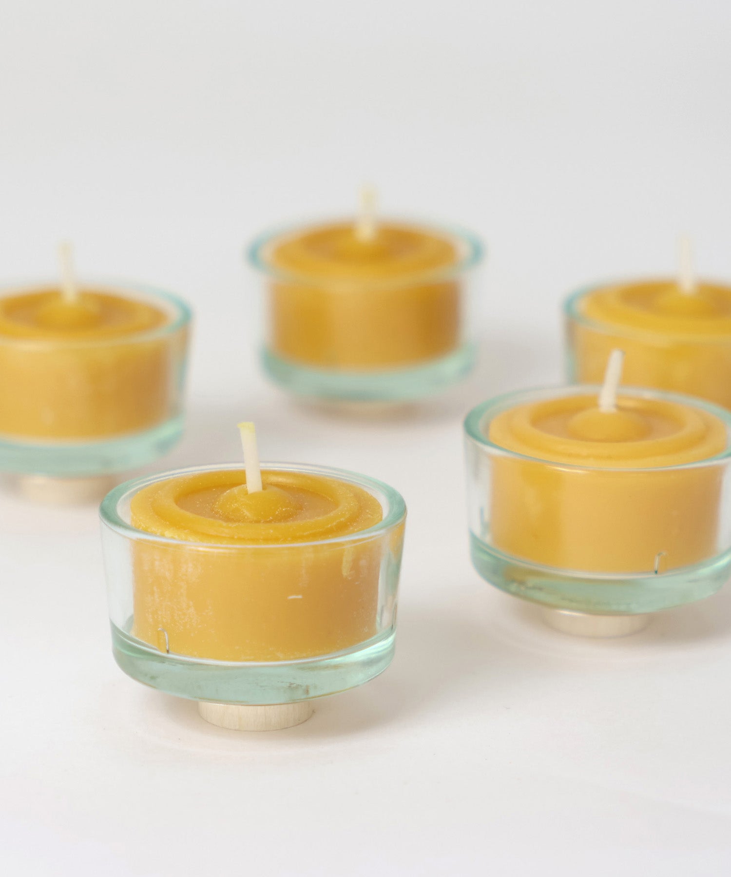 A closeup of the Grimm's beeswax tealights in the glass tealight holders.