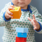 A close up of the orange wooden cube from the Haba blocks with sounds set.