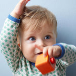 A child playing with the orange cube from the Haba blocks with sounds set