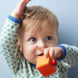 A child playing with the orange cube from the Haba blocks with sounds set