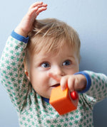 A child playing with the orange cube from the Haba blocks with sounds set