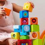 A child stacking the different coloured blocks from the Haba blocks with sounds set.