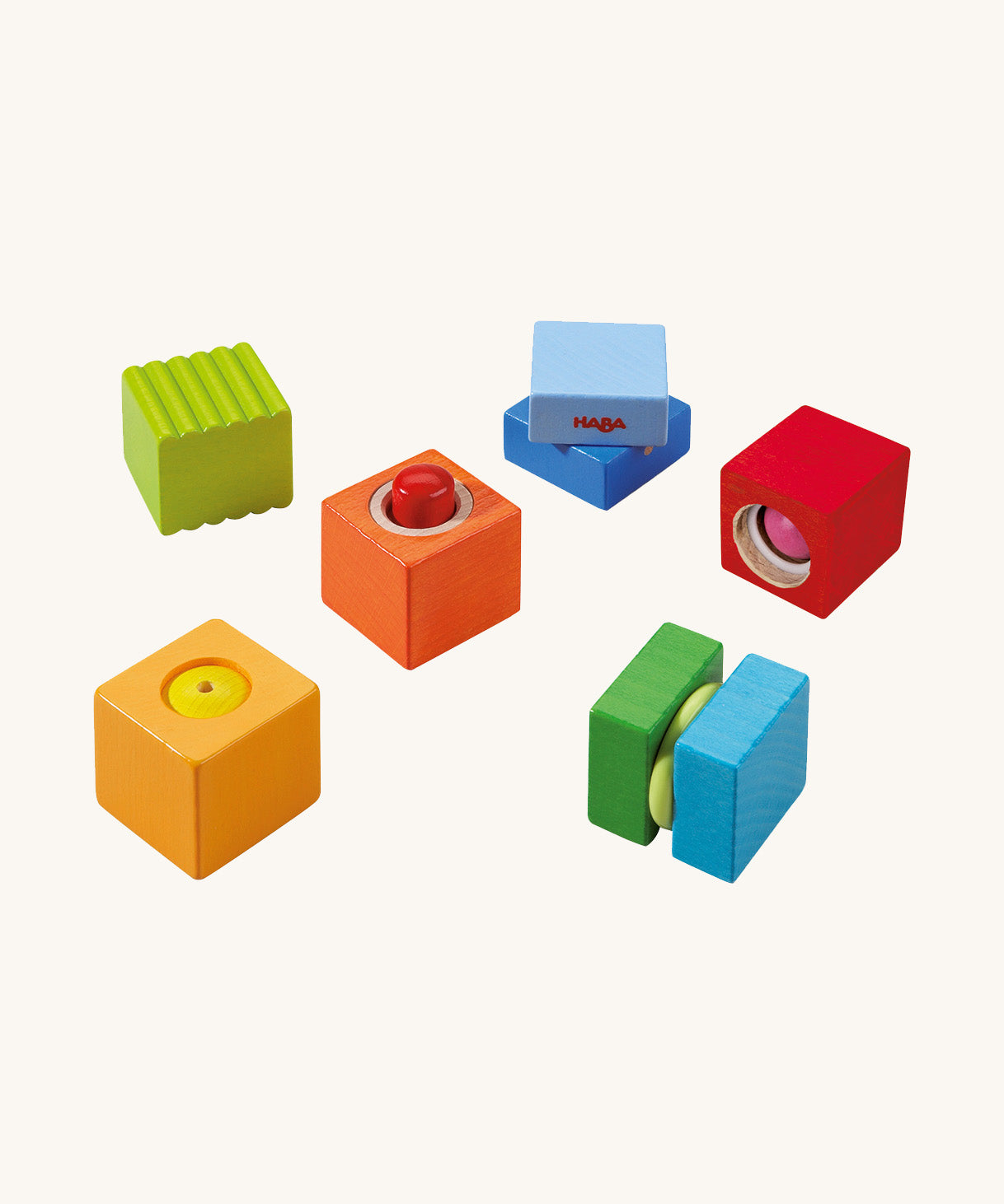 Green, orange, blue and red wooden cubes from the Haba blocks with sounds set on a cream background.
