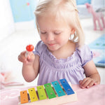  Xylophone Toy Instrument. A wooden drumming stick on top of a row of colourful flat metal bars pinned into a wooden base with each one being a different musical note