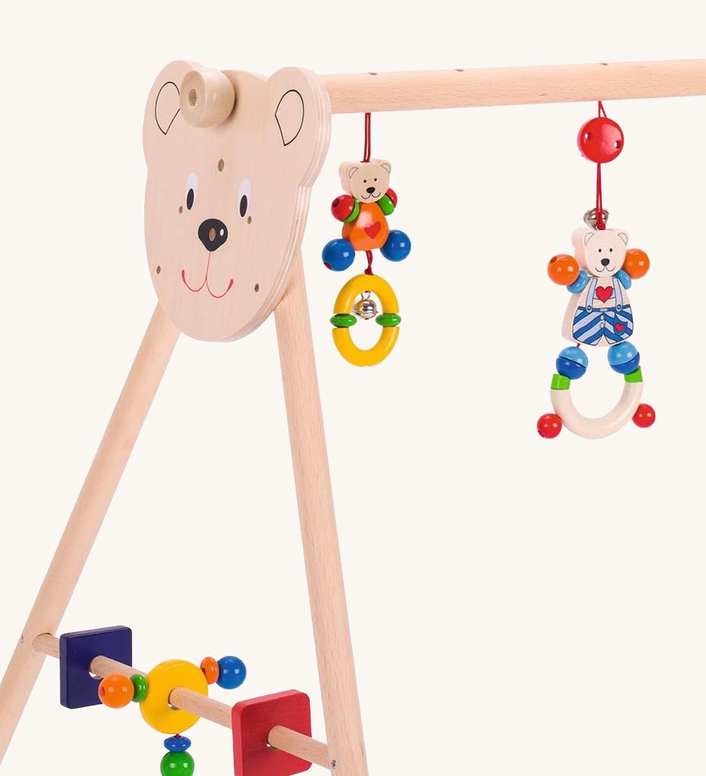 A close up of the details on the side of the Heimess wooden Baby Gym and Walker toy featuring a Heart Bear design. A baby gym and walker in one.
