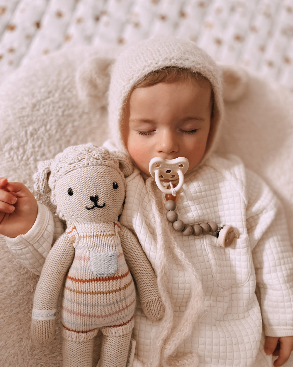 Close up of baby sleeping next to a cuddly toy with a dummy in his mouth