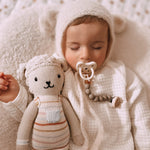 Close up of baby sleeping next to a cuddly toy with a dummy in his mouth