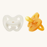 A two-pack of Hevea symmetrical teat baby pacifiers, made from 100% natural rubber and plastic-free. One in a milky white colour and one in a natural orange