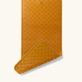 Hevea large natural rubber bath mat with corner flipped showing suction cups on the bottom, and a wave pattern on top for non-slip.