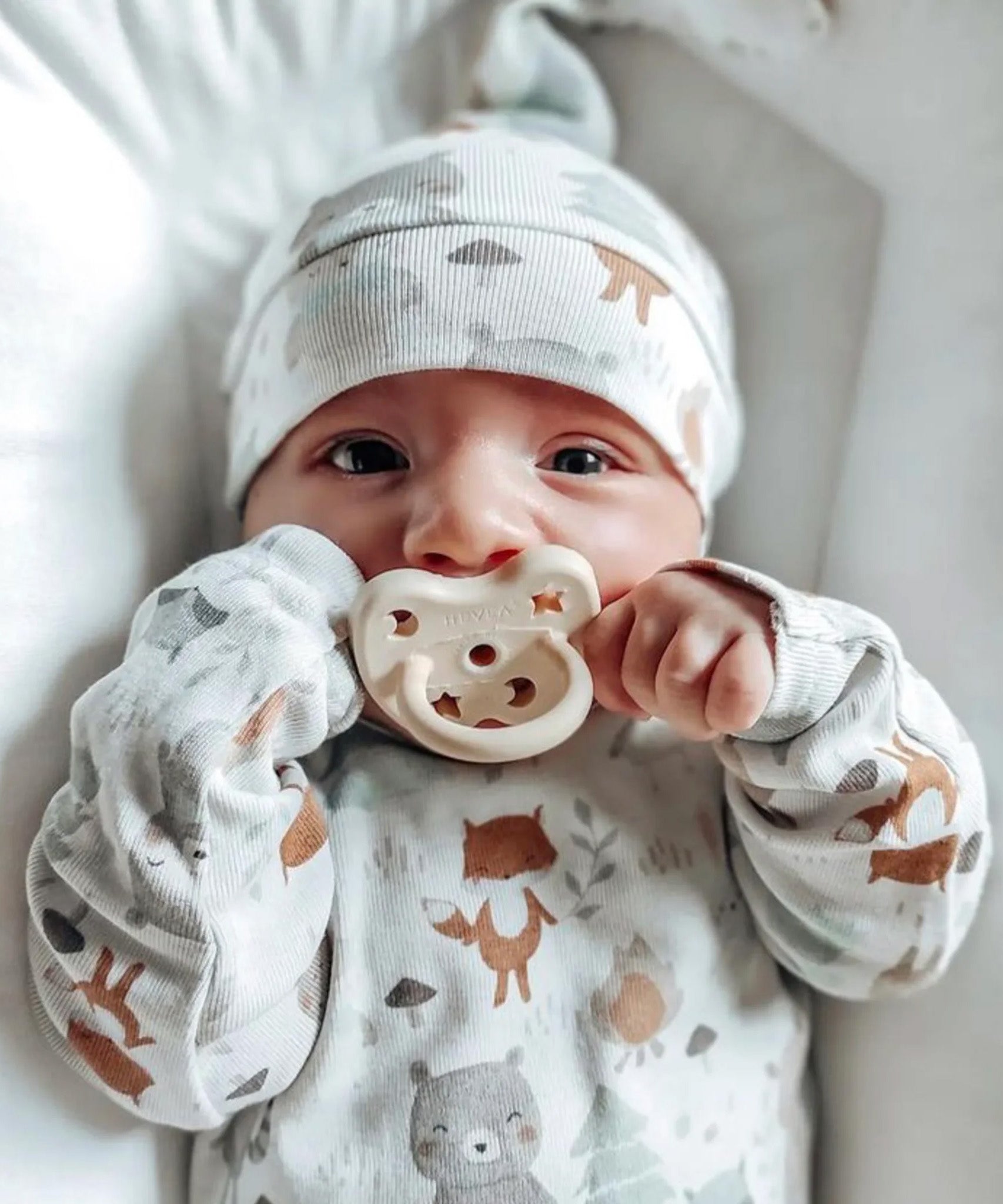A closeup of a baby with the Hevea natural rubber pacifier dummy with a symmetrical nipple shape, in milky white 