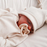 A sleeping baby with The Hevea natural rubber pacifier dummy with a symmetrical nipple shape, in milky white 