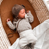 A sleeping baby in a crib with The Hevea natural rubber pacifier dummy with a symmetrical nipple shape in its mouth, in milky white colour 
