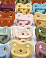 Close up of the Hevea natural rubber baby pacifiers in a row on a white background
