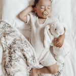 Young boy laying on a white bed with a Hevea natural rubber dummy in his mouth