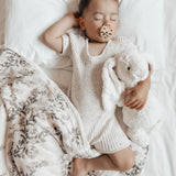 Young boy laying on a white bed with a Hevea natural rubber dummy in his mouth