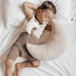 Young boy laying on a white bed with a Hevea natural rubber pacifier in his mouth