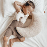 Young boy laying on a white bed with a Hevea natural rubber pacifier in his mouth