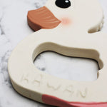 Close up of Hevea Natural Rubber Teether - Kawan the Duck  on a white marble background