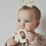 Baby with a bow in their hair holding Hevea Natural Rubber Teether - Kawan the Duck 