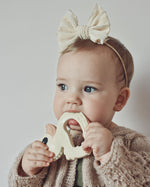 Baby with a bow in their hair holding Hevea Natural Rubber Teether - Kawan the Duck 
