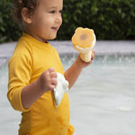 Hevea Upcycled rubber sand duck and sage frog toys being played in the pool by a small child