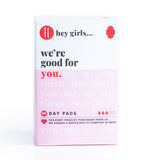 Hey Girls Natural Bamboo & Corn Fibre Disposable Day Pad open in someone's hand on a pink and red background