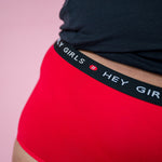 Hey Girls Super Soft Red Cherry Period Pants worn by a person with a black top on a pink background