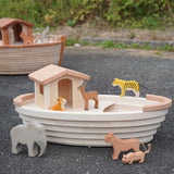 Holztiger handcrafted wooden Noah's ark with different animals on top and a XL ark in the background
