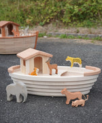 Holztiger handcrafted wooden Noah's ark with different animals on top and a XL ark in the background