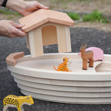 Adult placing the detachable cabin on top of the removable lid on the Holztiger Noah's ark showing animal figures surrounding the ark