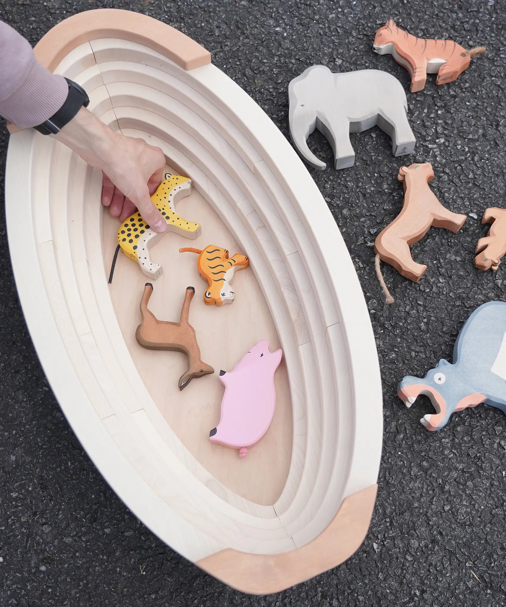 Holztiger wooden Noah's ark showing the removable lid off and a adult hand picking up a tiger figure inside