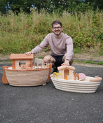 Adult kneeling behind the Holztiger handcrafted XL Noah's ark and the standard ark showing scale 