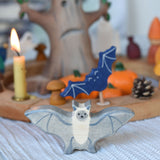 A Holztiger wooden bat toy figure placed on a striped tablecloth in front of a Halloween themed Grimm's celebration ring set up.
This wooden toy figure is part of a wide range of Holztiger figures and scenery perfect for small world play available here at Babipur 
