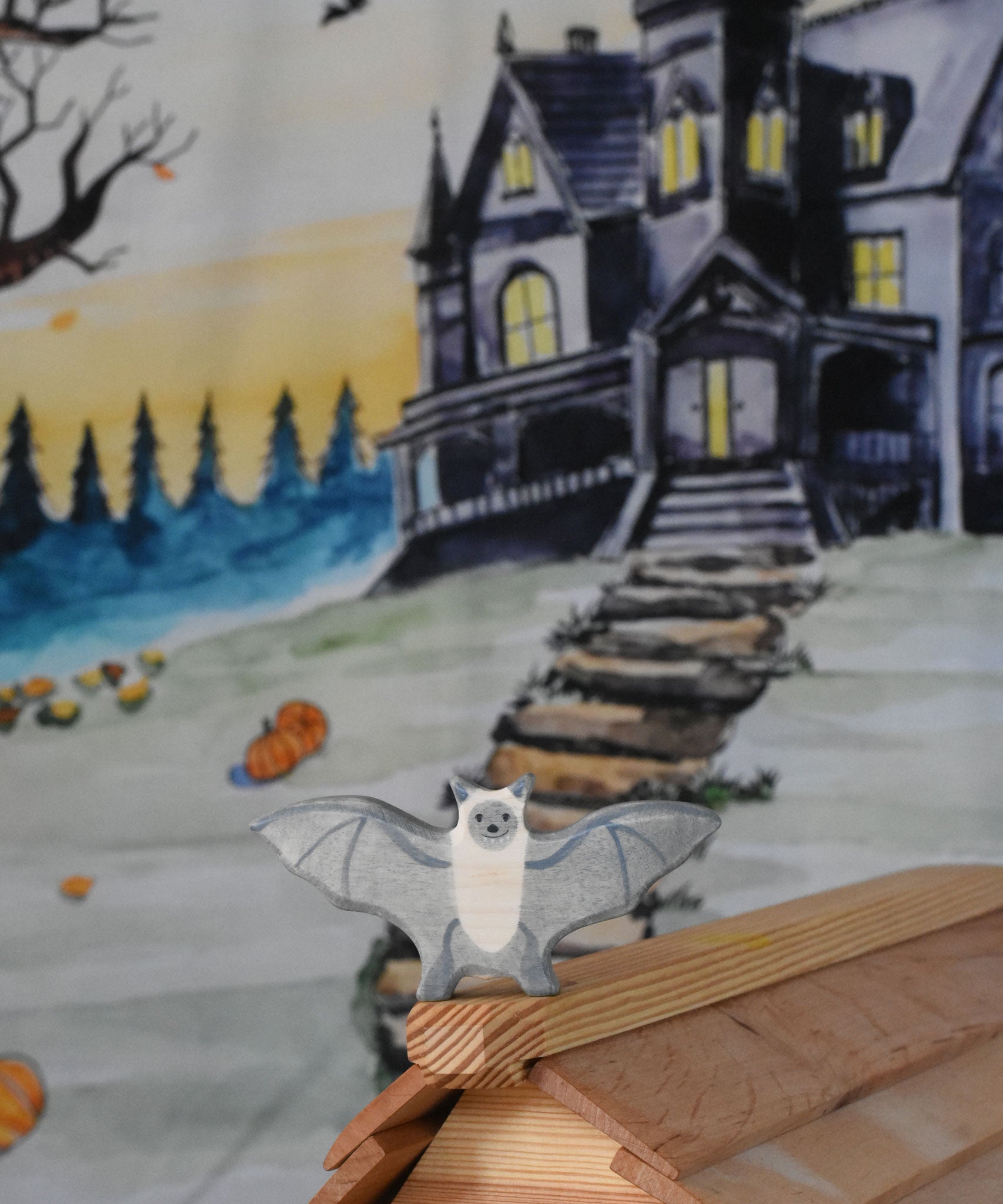 A Holztiger wooden bat toy figure placed on a ridge of the Ostheimer wooden cottage. A Wonderie Halloween trick or treat play cloth can be seen covering the wall behind.
This wooden toy figure is part of a wide range of Holztiger figures and scenery perfect for small world play available here at Babipur 