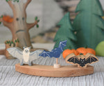 A Holztiger bat, Grimm's decorative bat figure and a Lanka Kade bat placed on a piece of a Grimm's celebration ring. 