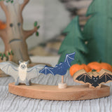 A Holztiger bat, Grimm's decorative bat figure and a Lanka Kade bat placed on a piece of a Grimm's celebration ring. 