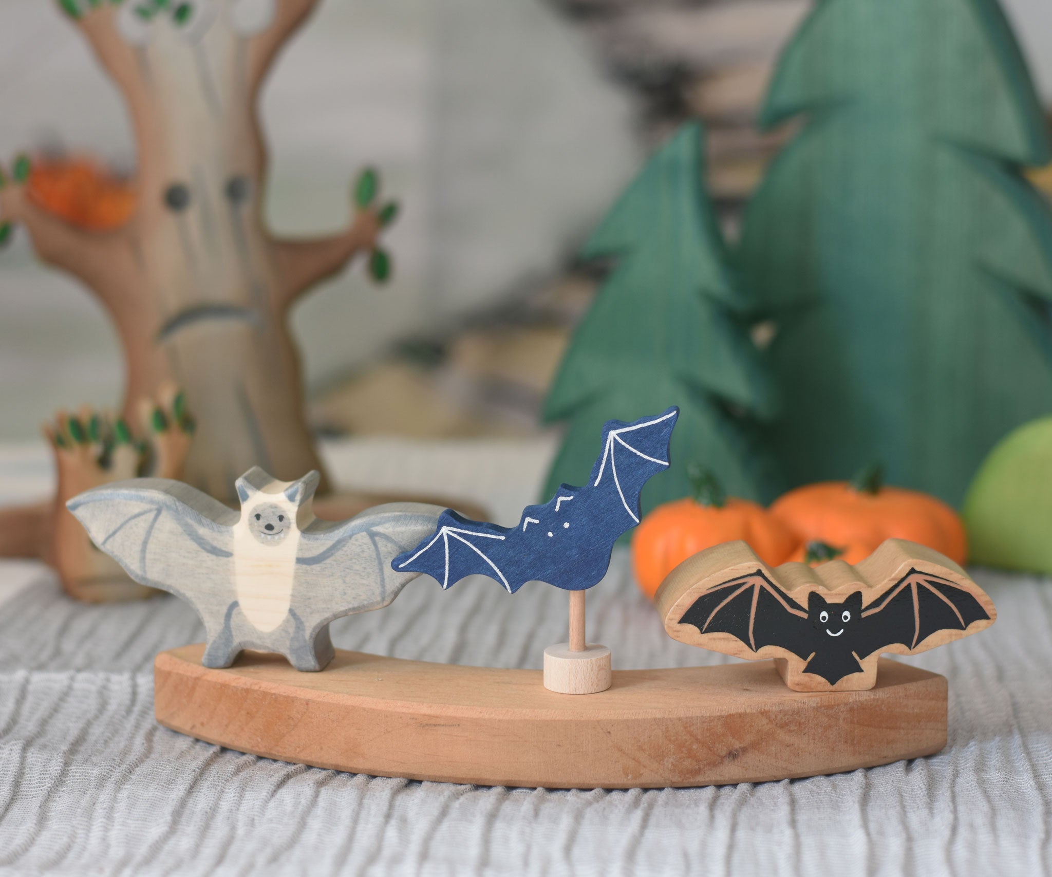 A Holztiger bat, Grimm's decorative bat figure and a Lanka Kade bat placed on a piece of a Grimm's celebration ring. 