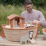 Adult playing with different animal figures on the Holztiger handcrafted XL Noah's ark showing the side ramp down