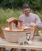 Adult playing with different animal figures on the Holztiger handcrafted XL Noah's ark showing the side ramp down