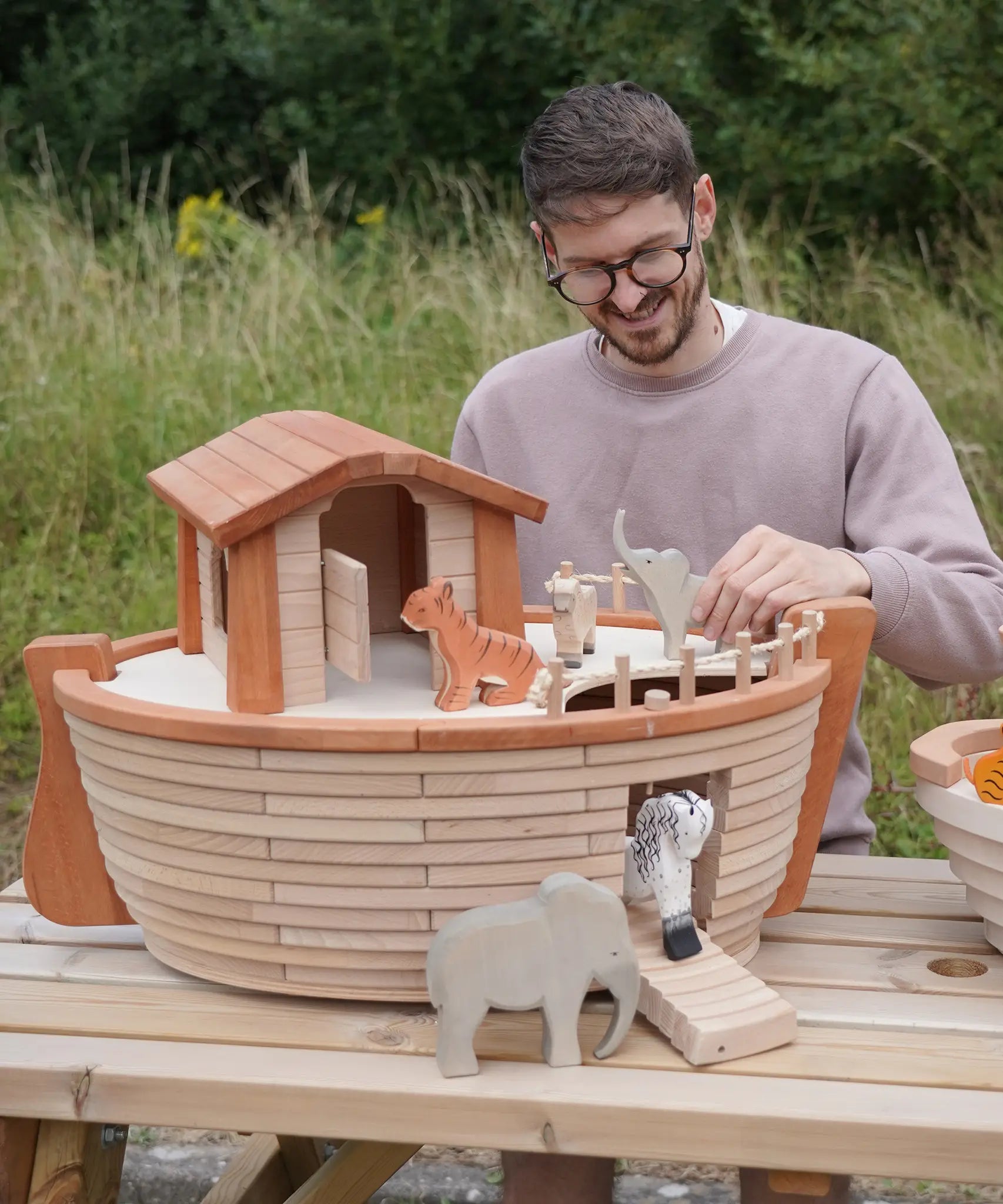 Adult playing with different animal figures on the Holztiger handcrafted XL Noah's ark showing the side ramp down