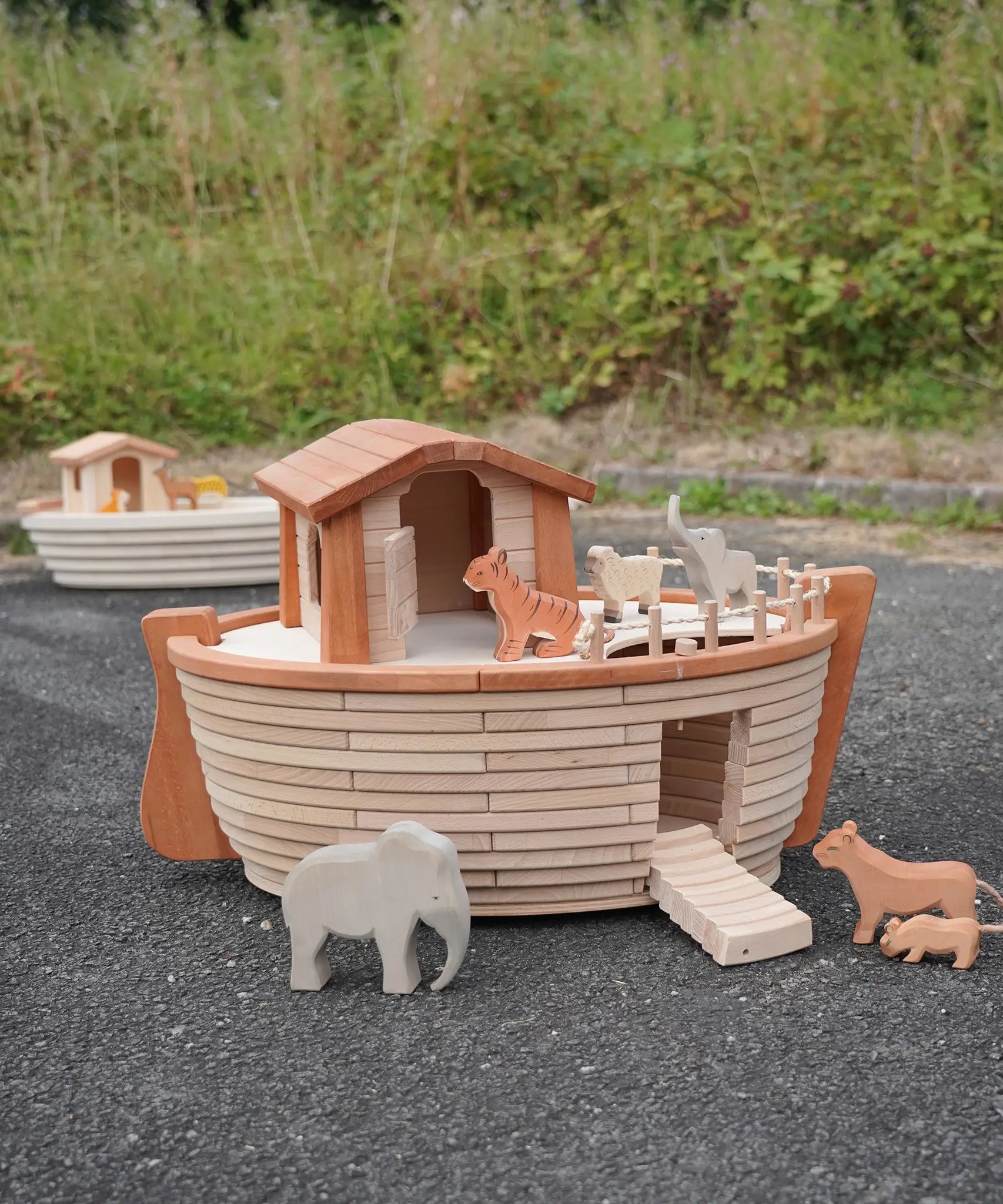 Holztiger handcrafted wooden XL Noah's ark with different animals on top  and side ramp down. Smaller ark in the background