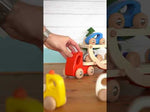 Close up of hand playing with the Bajo wooden transporter lorry toy on a wooden table